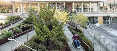 Wheelchair traveling on path of Lower Sproul stairway ramp.